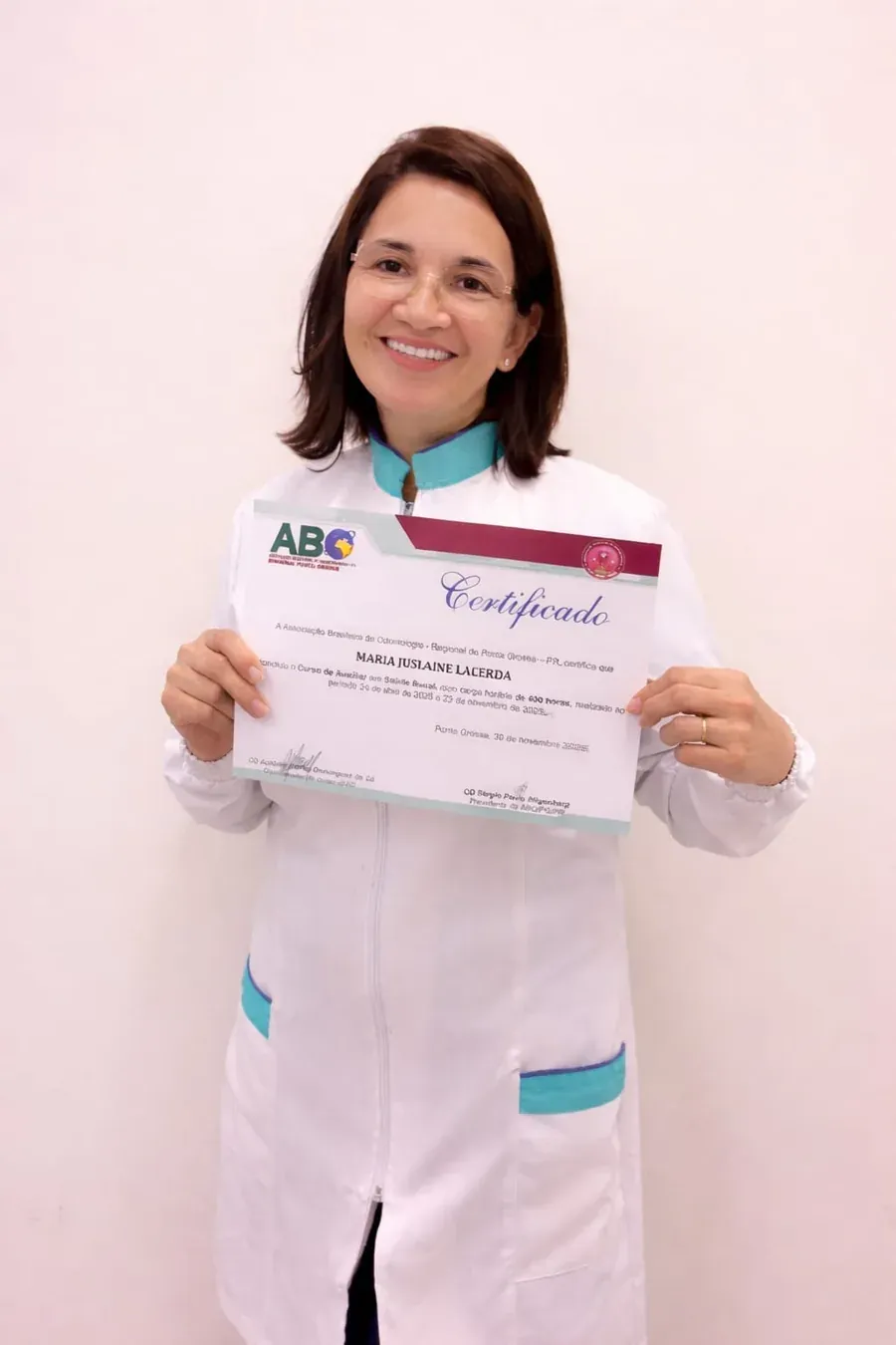 Aluna de jaleco branco segurando o certificado do Curso ASB