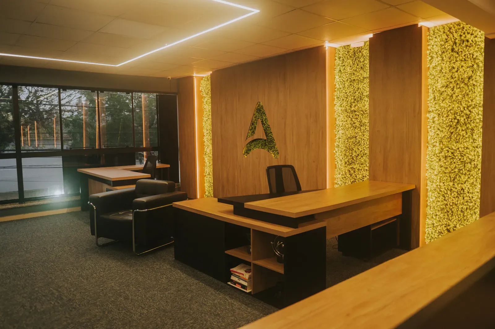 Sala da diretoria, com mesa de madeira e jardim vertical iluminado
