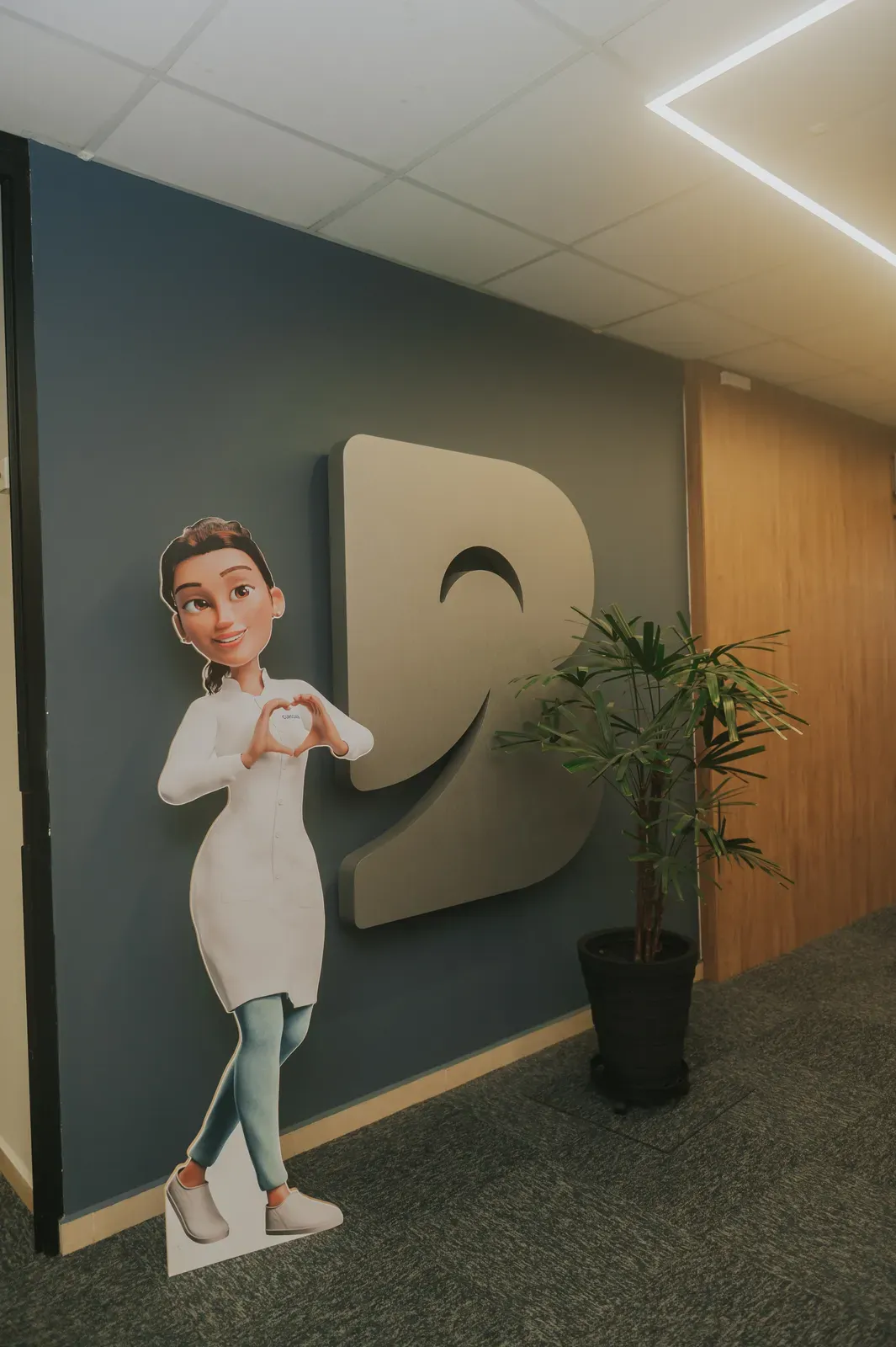 A Mari, assistente do Curso ASB, em tamanho real na entrada da escola, ao lado do logotipo